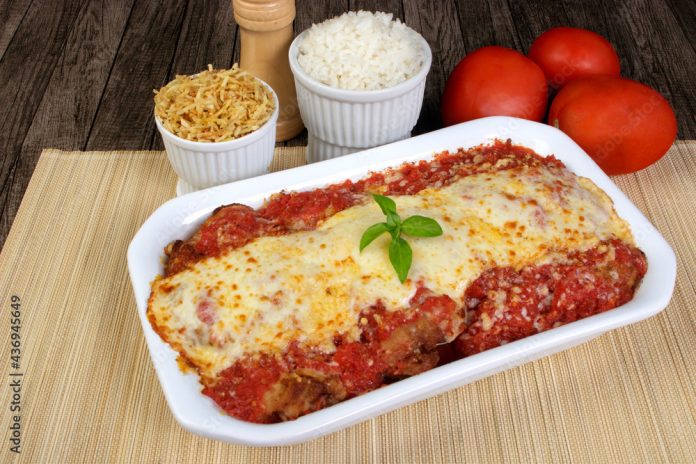 Steak Parmegiana or Parmegian Filet, made with breaded beef, red tomato sauce, mozzarella cheese and gratin Parmesan. Gourmet close-up photo. White rice and straw potatoes to accompany the food.