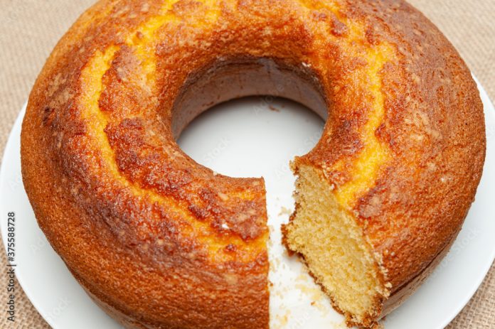 Cornmeal Cake (Bolo de Fuba) cut Brazilian style on a white plate. Isolated on jute. Top view. Close-up. Horizontal shot