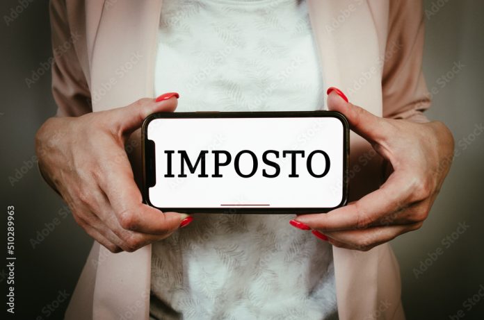 Business woman holding phone with Brazilian Portuguese word tax - imposto