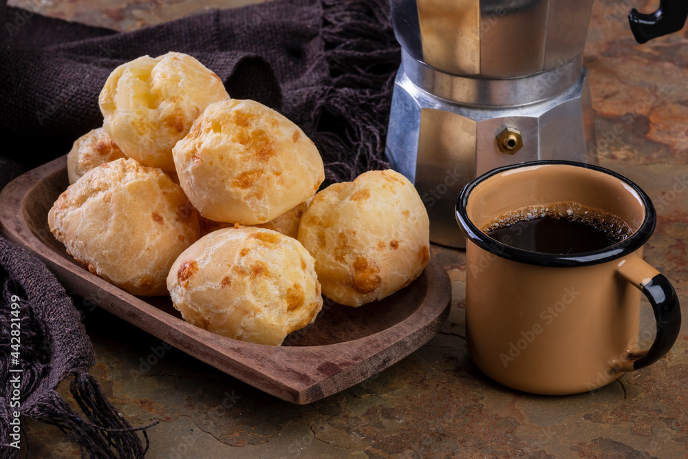 table with delicious cheese breads, a coffee mug and a traditional coffee maker