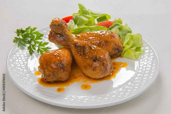 Coxas de frango grelhadas com salada no prato em fundo branco para recorte.
