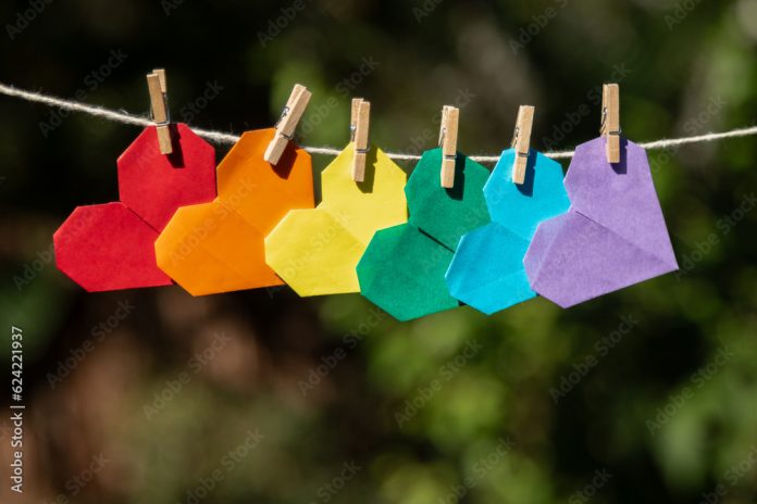 origamis de corações com as cores do arco-íris pendurados em um varal de barbante, simbolizando o amor e contra a homofobia e apoiando a causa LGBtQIAP+