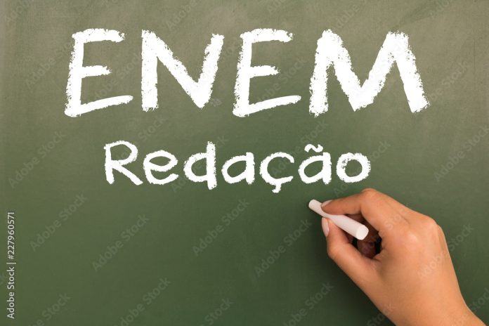 Female hand writing with chalk on empty green chalkboard. (translation portuguese: ENEM - National High School Exam Brazil - writing)