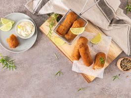 Meat croquets with garlic mayonnaise, lime slices to season and rosemary leaves on wooden table in a kitchen counter top.