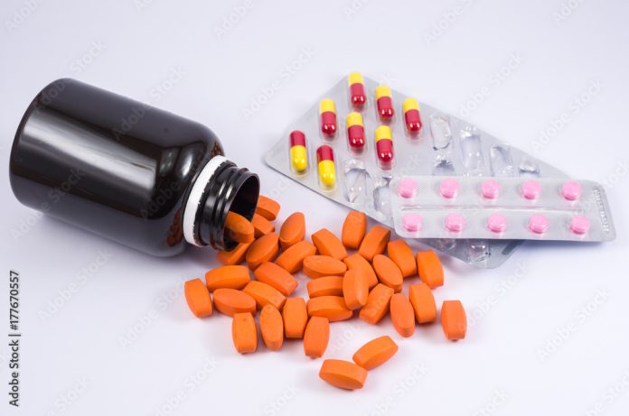 Frasco de remédios caído com comprimidos diversos em cápsulas, drogas.